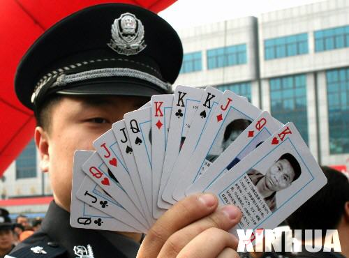 11月15日，一名警察在向群众展示印有被通缉命案逃犯头像的扑克牌。 当日，河南省荥阳市警方在郑州火车站将50万副印有被通缉命案逃犯头像的扑克牌交予铁路警方，由途经郑州站各次列车的乘警和乘务员向乘客发放，以达到发动群众协助警方捉拿逃犯的目的。 据介绍，用扑克牌通缉杀人逃犯这一追逃形式具有易引人注意、传播信息面广、持续时间长等优点。这次荥阳市警方印制的扑克牌上印有历年来涉案的16名杀人逃犯的资料，内容包括逃犯的头像、警方的报警电话、悬赏的数额等。 新华社记者王颂摄 