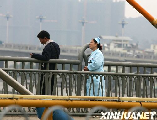 3月8日，在广西南宁市白沙大桥，扮成护士的女警察（右）正在劝说欲从距水面约30米高的桥上跳下的男子。当日，一名男子站在广西南宁市白沙大桥栏杆外面欲寻短见。警方接到市民报警后，派遣一名女警察扮成护士，接近男子开展劝说工作。经过近一个小时的劝说，欲寻短见的男子被成功解救。