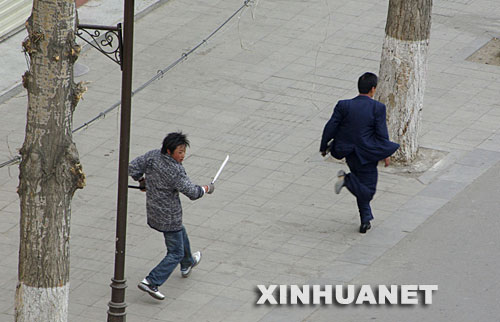 这张路透社播发的照片显示，3月14日，在拉萨市，一名不法分子手持长刀追赶行人。