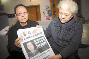 昨日，李罡父母拿着深圳当地的报纸向记者介绍小儿子生前情况。 本报记者 李斌 摄