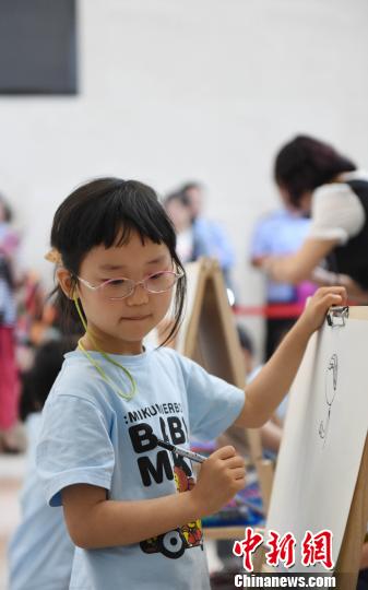 南京市公安局首届“警营文化周”上民警子女在用画板描绘自己的爸爸妈妈。　杨维斌 摄