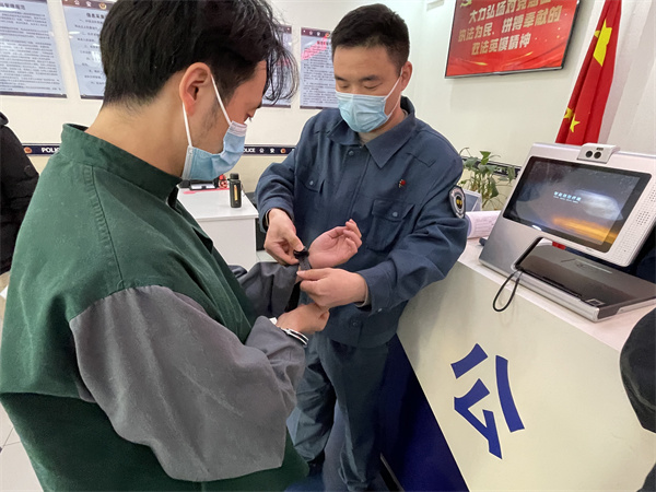 图为北京市海淀公安分局执法办案管理中心的工作人员为犯罪嫌疑人佩戴手环。