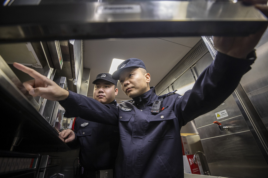 彭聪（右一）在乘警的配合下，对列车电器设备进行检查。胡勇摄