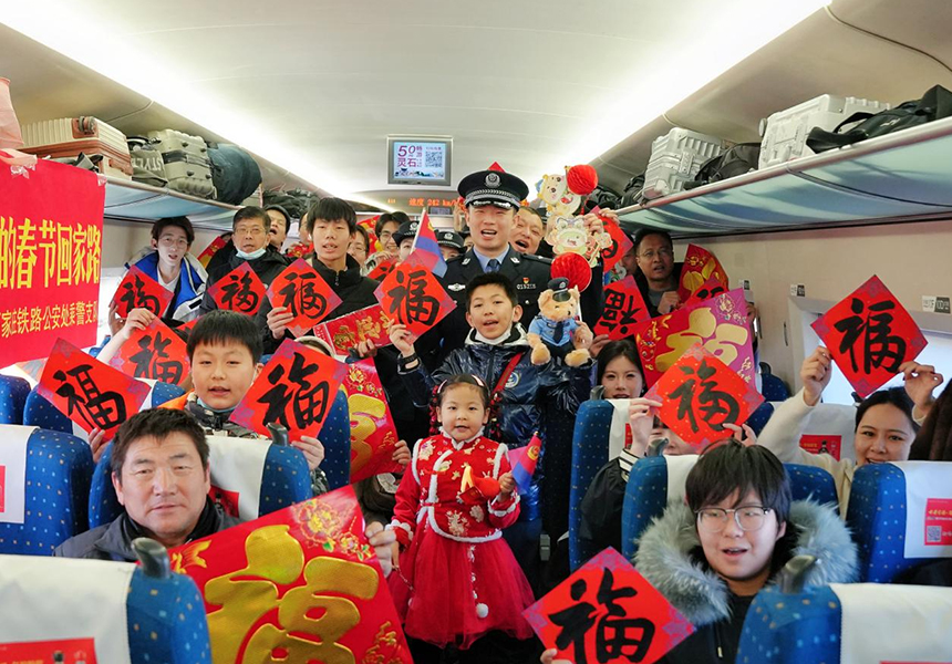 石家庄铁路公安处乘警支队民警在G2815次列车与乘客合影。实习生苑铭菲摄