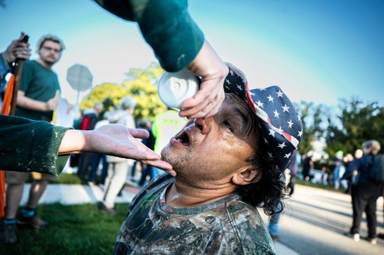9月26日，在位于美国芝加哥西郊布罗德维尤市的移民与海关执法局办事机构外，执法人员发射的催泪弹伤及一名抗议者，同伴在为他进行紧急处置。新华社发（文森特·约翰逊摄）